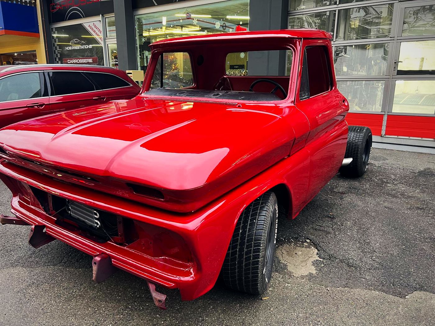 Pick-up rouge restauré par Rénov'Car devant le garage